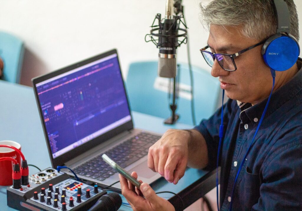 Independent podcaster recording an episode with a microphone and laptop