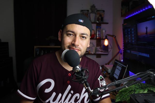 A smiling man recording a podcast in a modern audio studio in Santiago de Querétaro.