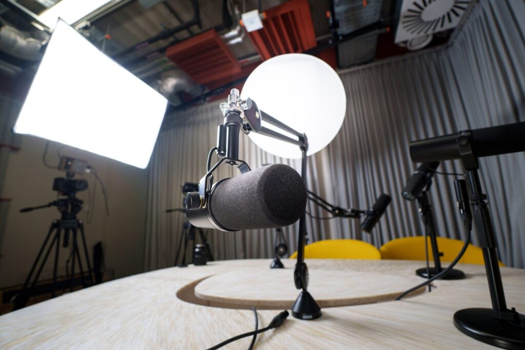 A modern podcast recording studio with microphones, chairs, and lighting equipment.